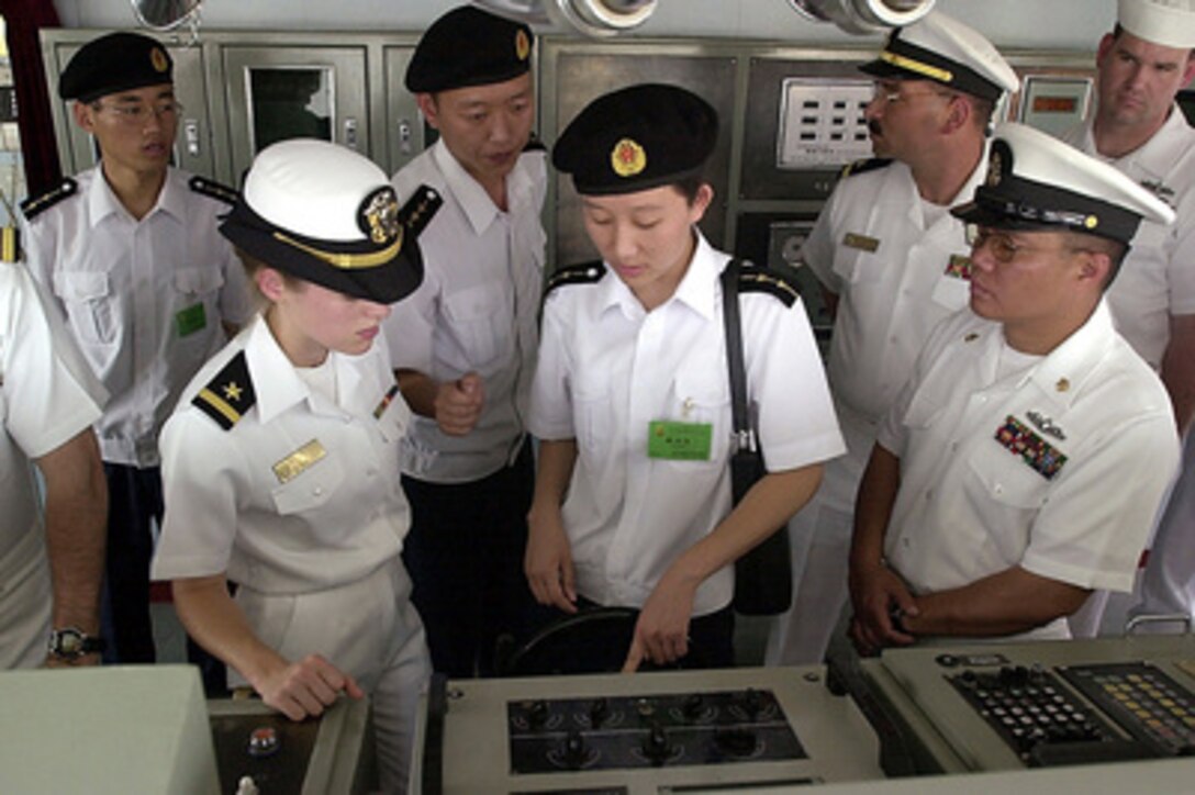 Lt. j.g. Weihua Hu (center), of the People's Liberation Army (Navy), shows Ensign Kathleen Merkle (left), U.S. Navy, the helm of the Chinese warship Haerbin (DDG 112) during a tour of the ship in Quingdao, China, on Aug. 3, 2000. Merkle and other crew members of the USS Chancellorsville (CG 62) are exchanging visits with the crew of the Haerbin while in port. 