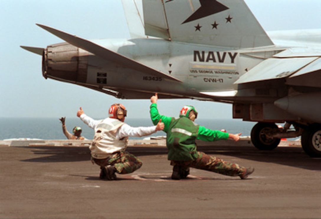 Petty Officers Ian Curphey and Brian Eads signal a thumbs-up for the launch of an F/A-18C Hornet from the flight deck of the aircraft carrier USS George Washington (CVN 73) while the ship conducts flight operations in the Persian Gulf on Aug. 12, 2000. Washington and its embarked Carrier Air Wing 17 are on station in the Persian Gulf in support of Operation Southern Watch, which is the U.S. and coalition enforcement of the no-fly-zone over Southern Iraq. Curphey, a Navy Aviation Structural Mechanic 1st Class, is from Anchorage, Alaska. Eads, a Navy Aviation Structural Mechanic 2nd Class, is from Houston, Texas. The Hornet is attached to Strike Fighter Squadron 81 of Oceana Naval Air Station, Va. The Washington is deployed from its home port of Norfolk, Va. 
