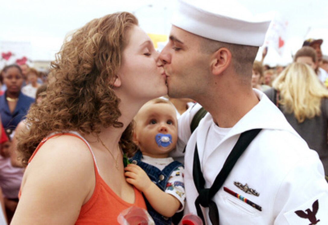 "Yeah, that's my dad," little Michael Standfill (center) seems to say as he intently watches his father Petty Officer 2nd Class Michael Standfill kiss his wife Terri during their reunion on the pier in Norfolk, Va., on Aug. 18, 2000. Michael's father, who is a Navy operations specialist, just returned from six-month deployment to the Mediterranean Sea and Persian Gulf aboard the USS Mahan (DDG 72). The Mahan was one of nine ships assigned to the USS Dwight D. Eisenhower Carrier Battle Group which enforced no-fly zones over the former Yugoslavia and Southern Iraq. 
