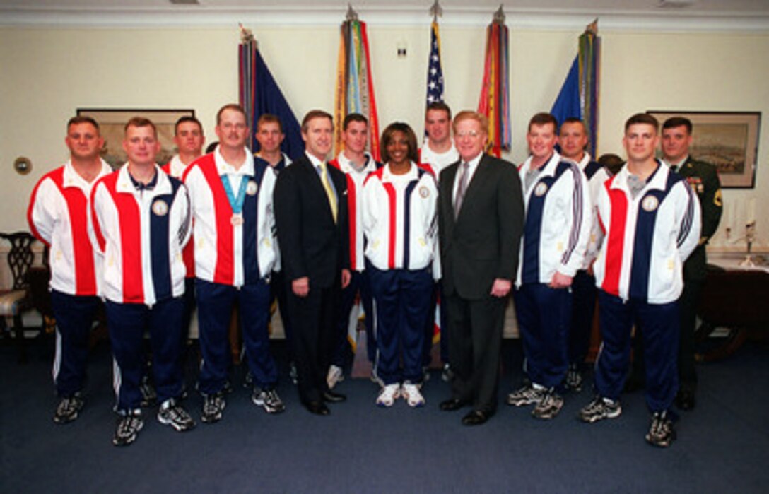 Secretary of Defense William S. Cohen (left) and Deputy Secretary of Defense Rudy de Leon (right) pose for photographs with military athletes who competed in the Summer 2000 Olympic Games held in Sydney, Australia, as they visit Cohen's office in the Pentagon on Nov. 28, 2000. The Olympians will take a special guided tour of the Pentagon following the meeting. 