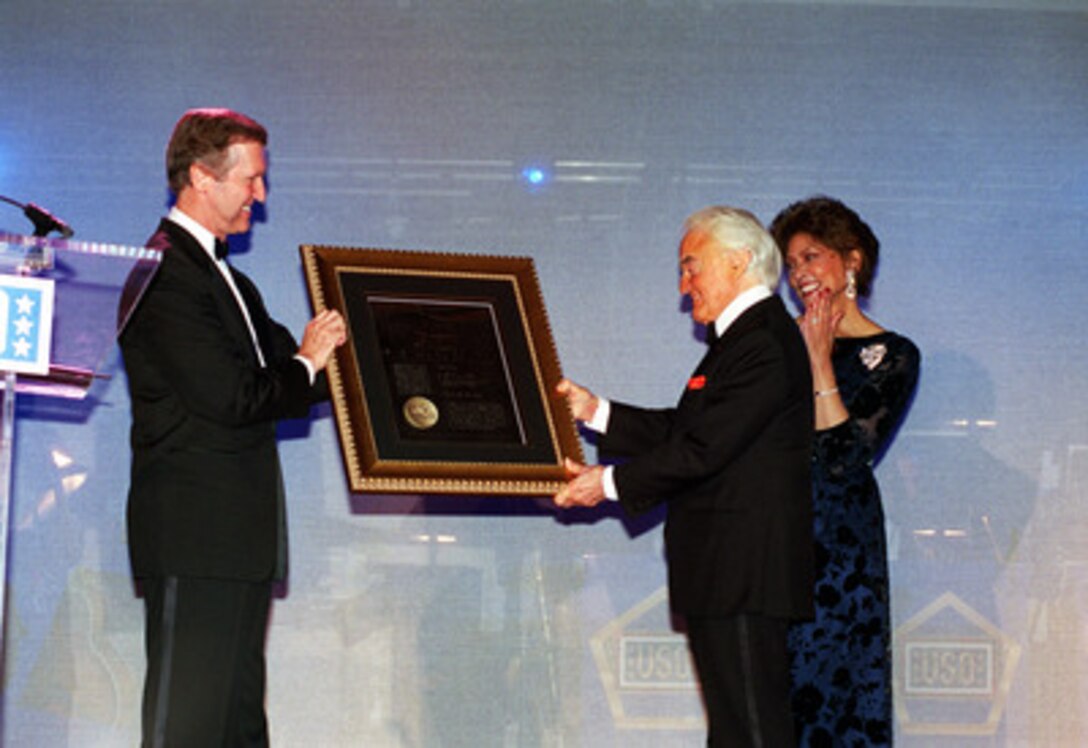 Secretary of Defense William S. Cohen (left) presents the first Citizen Patriot Award to Jack Valenti as Janet Langhart Cohen applauds on Nov. 30, 2000, in Beverly Hills, Calif. Valenti, who is president of the Motion Picture Association of America, was presented the award for his efforts to encourage positive portrayal of the U.S. military through film and television. Cohen co-hosted the ceremony and dinner with the United Service Organizations. 