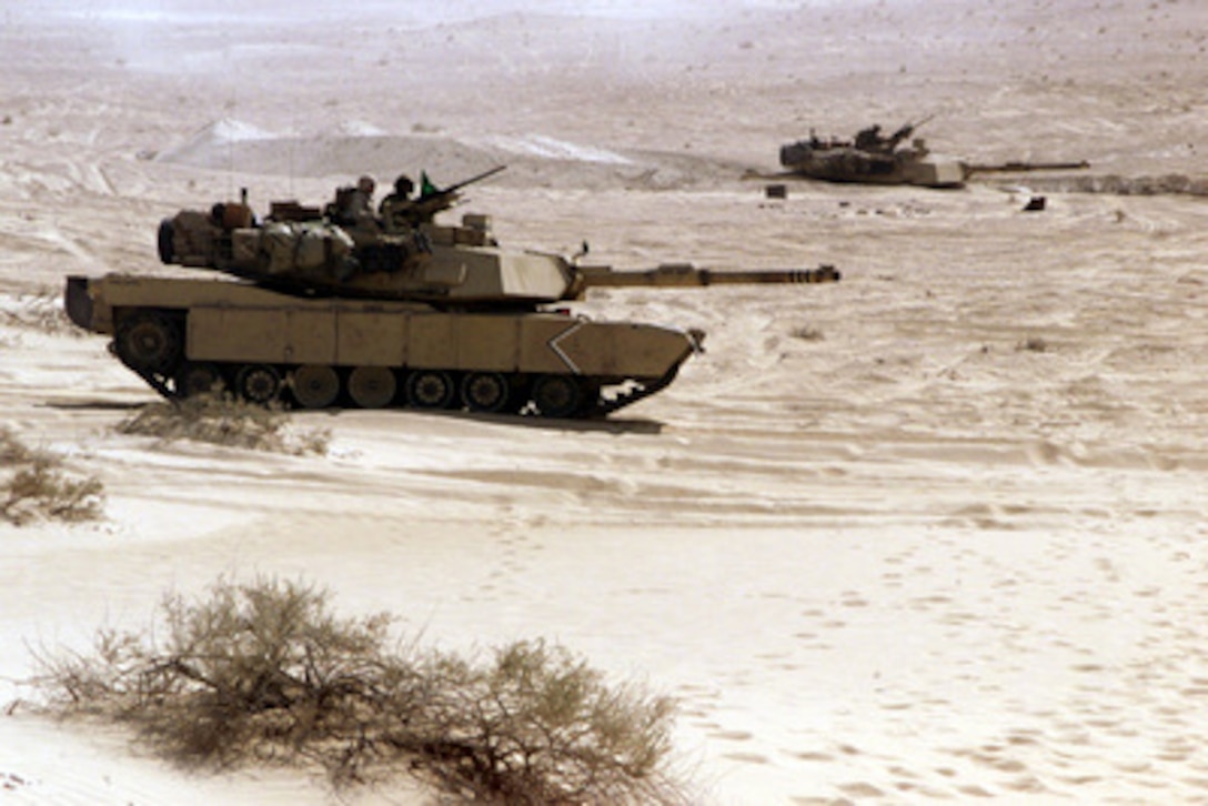 Two U.S. Marine Corps M1-A1 Main Battle Tanks sit in defensive positions as they prepare to engage targets on Range 2 of the Al Hamra Training Area in the United Arab Emirates on Nov. 22, 2000. U.S. Marines from the 13th Marine Expeditionary Unit (Special Operations Capable) are deployed from the USS Tarawa (LHA 1) to the training area for Exercise Iron Magic. 