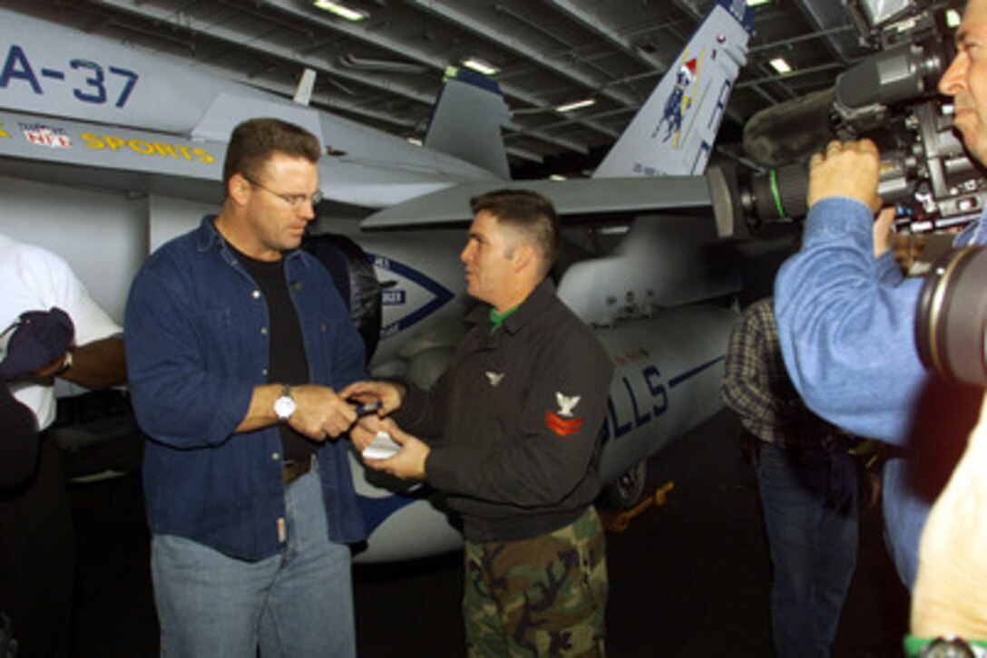 Fox Sports celebrity Howie Long (left) signs an autograph for a crew member in the hangar deck of the USS Harry S. Truman (CVN 75) on Dec. 14, 2000. Long is aboard the aircraft carrier to tape the National Football League Pre-Game Show to be aired on the Fox network on December 16th and 17th. The Truman Battle Group is operating in the Mediterranean Sea on a scheduled six-month deployment. 