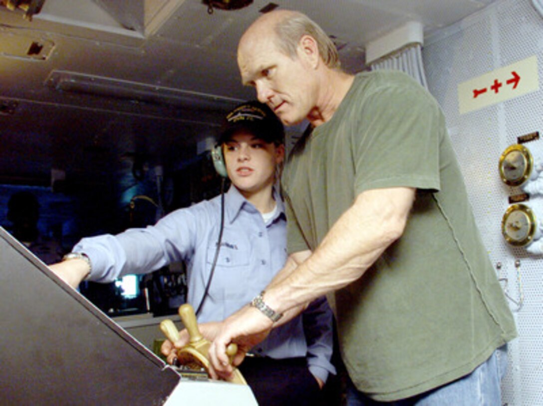 Fox Sports celebrity Terry Bradshaw (right) tries his hand at steering the USS Harry S. Truman (CVN 75) under the watchful eye of Seaman Blair C. Mammel on Dec. 14, 2000. Mammel, who is a qualified ship's helmsman, gave Bradshaw some pointers on steering the aircraft carrier, which is nearly four football fields long. Bradshaw is aboard the aircraft carrier to tape the National Football League Pre-Game Show to be aired on the Fox network on December 16th and 17th. The Truman Battle Group is operating in the Mediterranean Sea on a scheduled six-month deployment. Mammel is from Billings, Mont. 