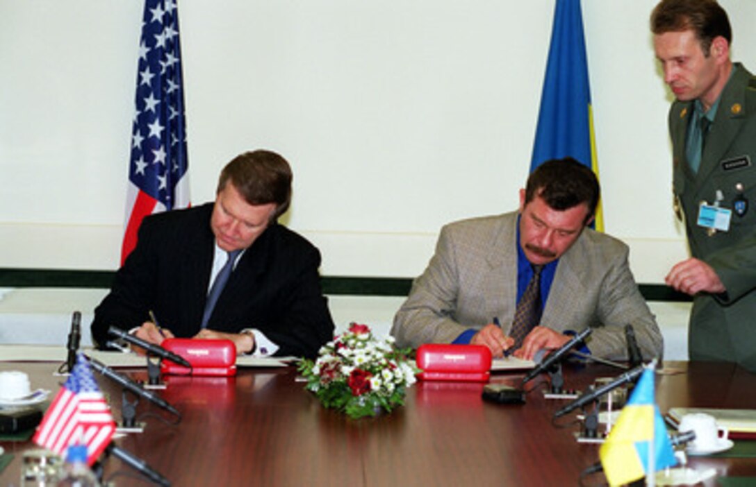 Secretary of Defense William S. Cohen (left) and Ukrainian Defense Minister General Colonel Oleksander Kuzmuk sign an annual Plan of Cooperation between the U.S. Department of Defense and the Ukrainian Ministry of Defense at NATO Headquarters in Brussels, Belgium, on Dec. 5, 2000. The bilateral plan sets out defense and military cooperation activities between the two countries for the coming year. This is Cohen's last scheduled trip to NATO Headquarters as defense secretary. 