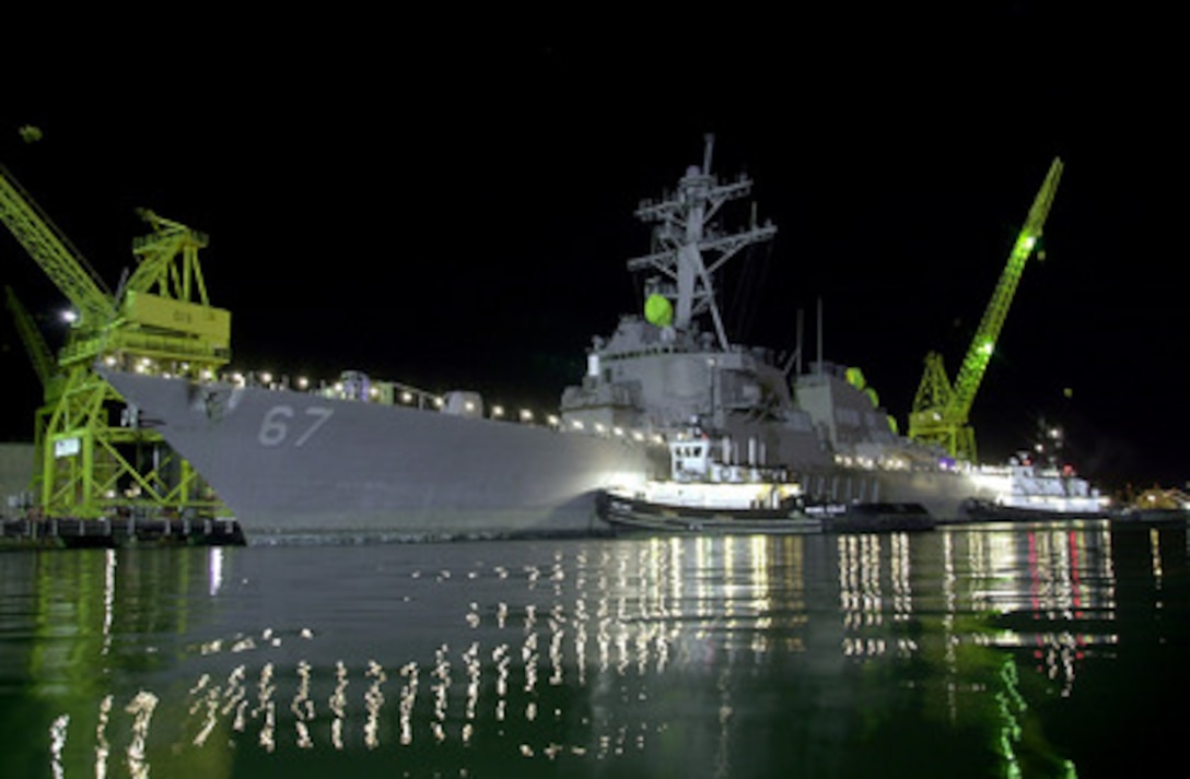 Two tug boats gently push the USS Cole (DDG 67) to its mooring at Pier 4 of the Ingalls Shipyard in Pascagoula, Miss., on Dec. 24, 2000. The Arleigh Burke class destroyer was the target of a terrorist attack in the port of Aden, Yemen, on Oct. 12, 2000, during a scheduled refueling. The attack killed 17 crew members and injured 39 others. The Cole was transported from Aden to Pascagoula by the Norwegian heavy transport ship M/V Blue Marlin. A 60 foot by 60 foot patch was welded to the hull of the destroyer before it was off loaded from the Blue Marlin. 