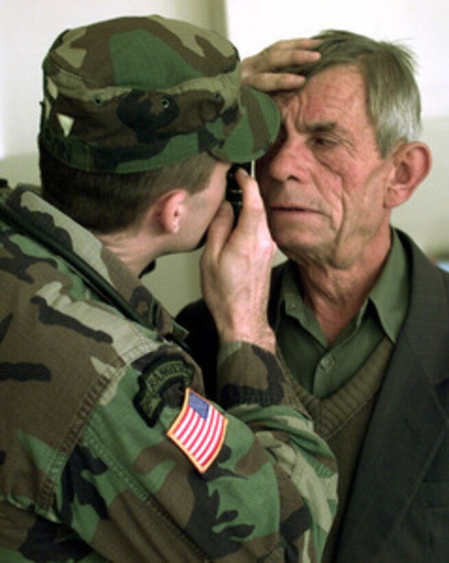 Lt. James Slevin, U.S. Army, evaluates the eyes of a local man seeking medical attention in Gornje Kosce, Kosovo, on Jan. 19, 2000. Slevin and other members of Headquarters Company, 1-63 Armored Battalion, Medical Platoon, worked at a school in Gornje Kosce to provide local people with first aid and treatment. Slevin is deployed from Vilseck, Germany, to Kosovo as part of KFOR. KFOR is the NATO-led, international military force in Kosovo on the peacekeeping mission known as Operation Joint Guardian. 
