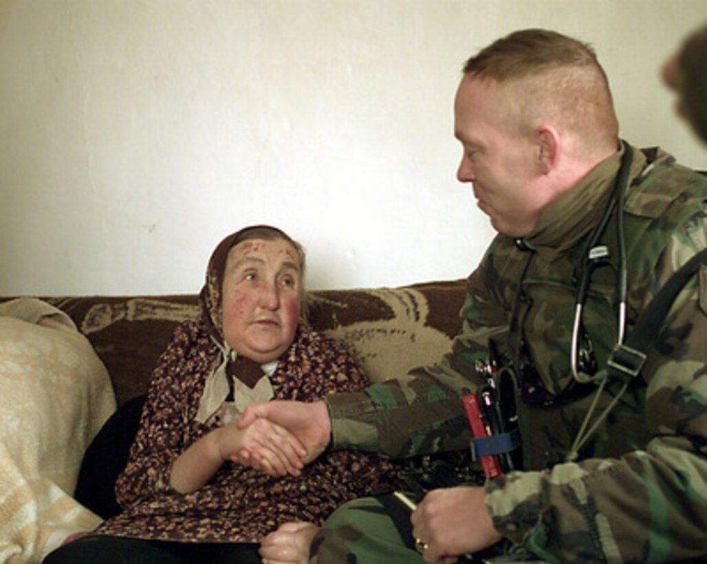 A Gypsy woman from Nova Brdo, Kosovo, thanks Capt. Peter Buckley, U.S. Army, for the medical attention she received on Jan. 21, 2000. Members of the 1-63 Armor Battalion Medical Platoon conducted clinic in a school building in the remote mountain village of Nova Brdo providing medical aid to people in the area who are normally out of reach of medical care. Buckley and members of his platoon are deployed to Kosovo as part of KFOR. KFOR is the NATO-led, international military force in Kosovo on the peacekeeping mission known as Operation Joint Guardian. 