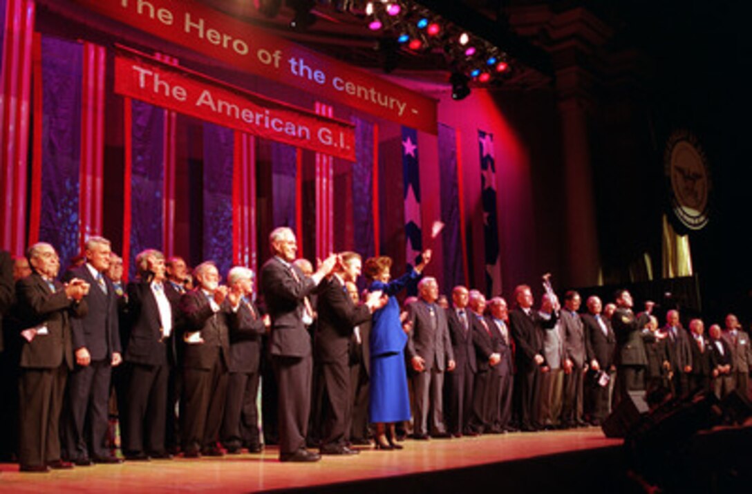 Historian Stephen E. Ambrose (left), Secretary of Defense William S. Cohen (center) and his wife Janet Langhart Cohen (right) join 57 Medal of Honor recipients on the stage during the finale of the Pentagon Pops in Washington, D.C., on Feb. 21, 2000. Cohen and his wife hosted the Pentagon Pops, a musical salute with the theme of The Hero of the Century--the American G.I., at the Daughters of the American Revolution Constitution Hall. 