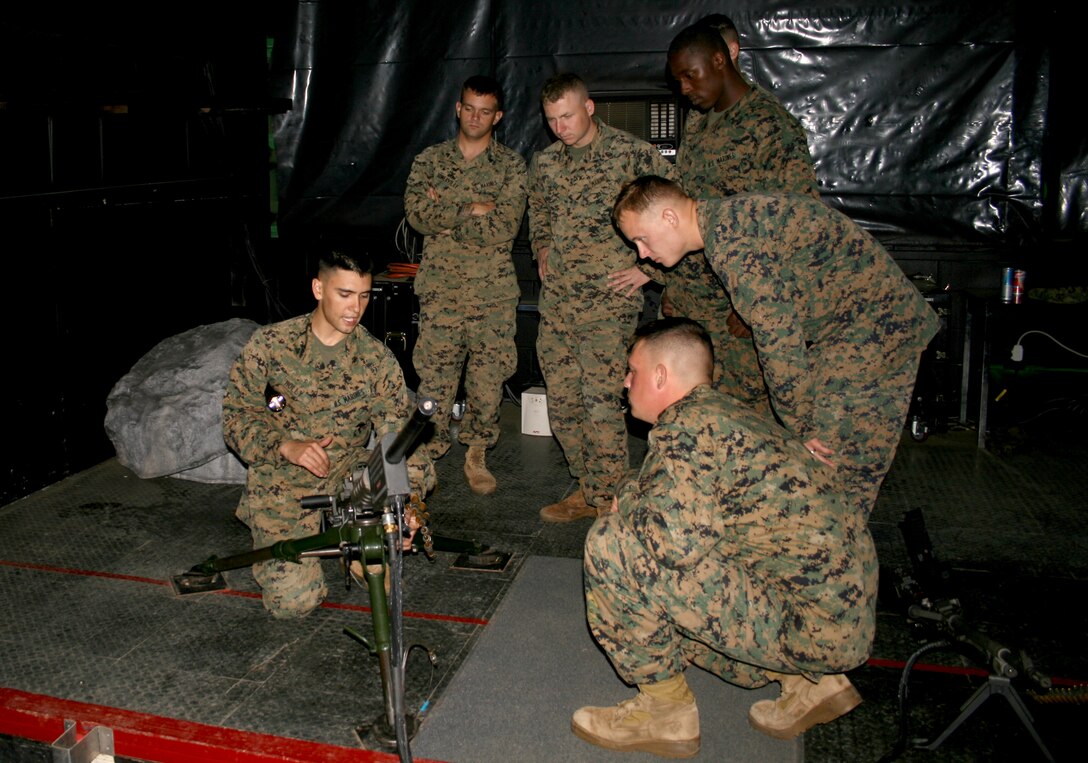 Cpl. Randall Holly (left) demonstrates how to operate the modified.50 caliber machine gun in the 3rd Marine Regiment's Indoor Simulated Marksmanship Trainer Feb. 27.  Marines from MARFORPAC practiced firing on the ISMTfor two days, firing on a variety of courses and weapon systems.