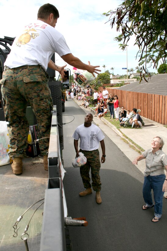 HONOLULU- Elaine Masaki tosses a bag of toys to Sgt Jose Godinez of 4th Force Reconnaissance Company during the Hawaii Kai Christmas Parade Nov. 29.  The Marines collected toys along the route and at the Koko Marina Shopping Center in support of the Toys for Tots campaign.  This year's goal is 40,000 toys.  Anyone interested in donating can visit www.toysfortots.org.