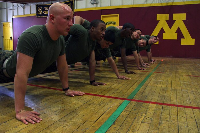 Pfc. Jeremy Amundson, Pvt. Cecil Howard, Pvt. Joel Tores, Pvt. Deshawn Henderson, Pvt. Chue Yang, Pfc. Chue Xiong, Pfc. Jared Jackson and Pfc. John Doran demonstrate how to properly execute a group exercise at the University of Minnesota Armory Dec. 18. More than 30 people, including these eight Marines who recently completed boot camp, attended the poolee function. Service members have been training at the armory since it was built in 1896.