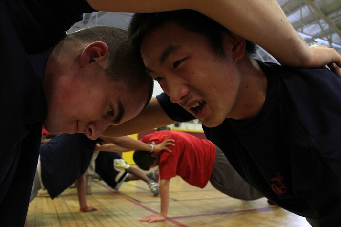 Roseville, Minn., Delayed Entry Program Poolees Justin Scherkenbach and Robert Xiong work together to perform a one-handed push-up at the University of Minnesota Armory Dec. 18. More than 30 people, including a few Marines who recently completed boot camp, attended the poolee function. The Marine Corps established the Delayed Entry Program to help men and women prepare for the mental and physical challenges of boot camp.