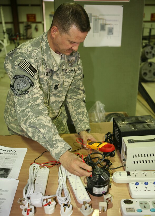 Petty Officer 1st Class Charles Perez, the leading petty officer for the Base Command Group electrical section, demonstrates an electrical test during the II Marine Expeditionary Force Headquarters Group (Forward) safety exposition aboard Al Asad Air Base, Iraq, Dec. 18, 2009. II MHG (Fwd) held the safety exposition to combat complacency among service members nearing the end of their deployment.