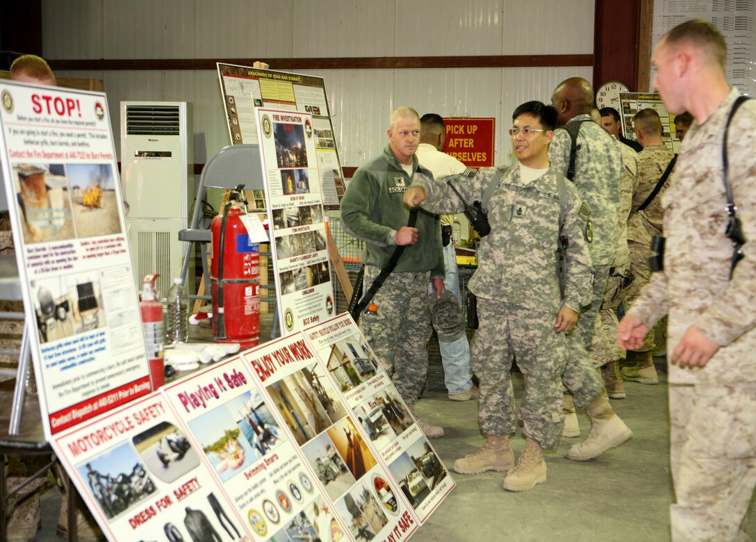 Service members make their way through static displays and information tables at the II Marine Expeditionary Force Headquarters Group (Forward) safety exposition aboard Al Asad Air Base, Iraq, Dec. 18, 2009. II MHG (Fwd) held the safety exposition to combat complacency among service members nearing the end of their deployment.