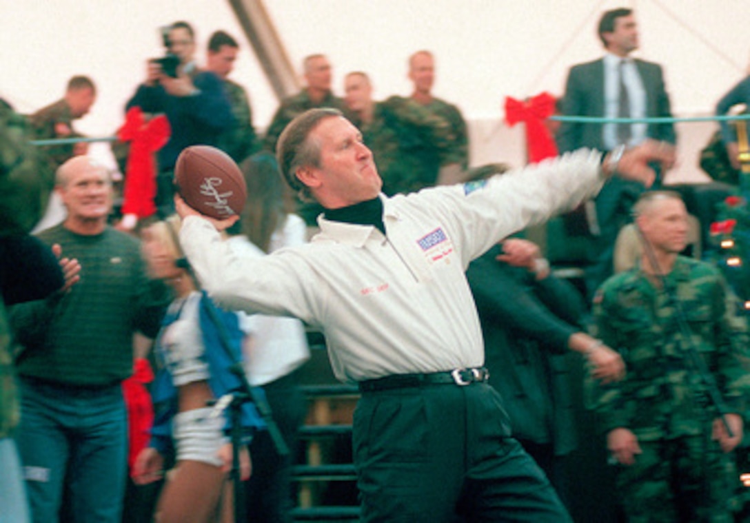 Secretary of Defense William S. Cohen throws an autographed football into the audience during a United Service Organizations (USO) show in the Eagle Sports Complex at Tuzla Air Base, Bosnia and Herzegovina, on Dec. 22, 1999. An entourage of entertainers, cheerleaders, sports figures, comedians, and a super model joined Cohen on his third annual holiday tour and USO show. 
