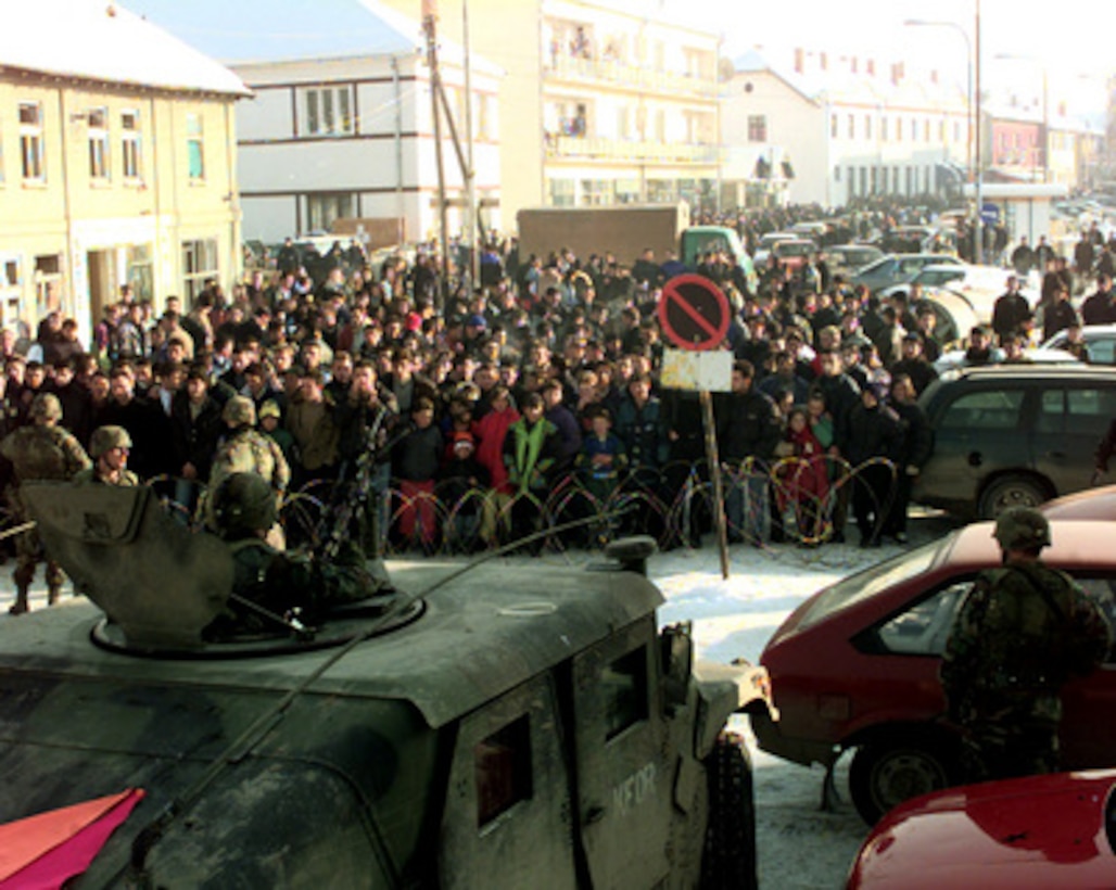 Soldiers of the 504th Parachute Infantry Regiment maintain crowd control as residents of Vitina, Kosovo, protest in the streets on Jan. 9, 2000. The protesters were demanding the release of local Albanians held in custody for questioning. The soldiers are attached to the 82nd Airborne Division, Fort Bragg, N.C., and are deployed to Kosovo as part of KFOR. KFOR is the NATO-led, international military force in Kosovo on the peacekeeping mission known as Operation Joint Guardian. 