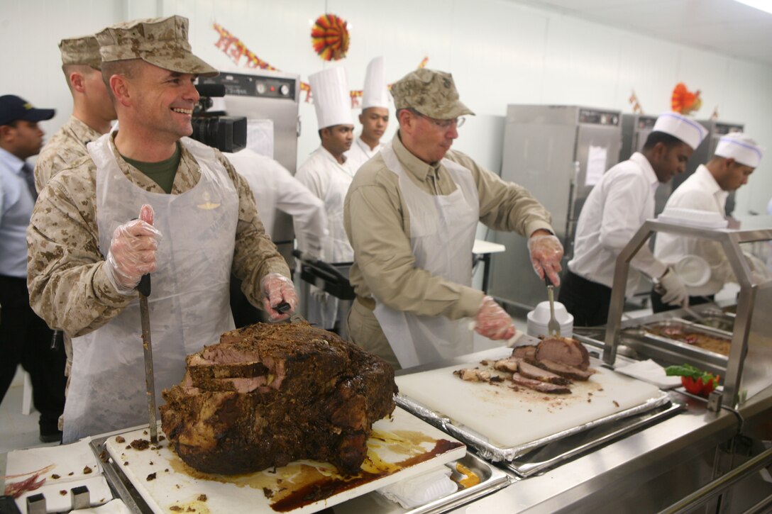 Secretary of the Navy Donald C. Winter and Lt. Col. Chris Hastings, commanding officer, 1st Battalion, 4th Marine Regiment, Regimental Combat Team 1, serve Marines with 1st Battalion, 4th Marine Regiment, Regimental Combat Team 1, a Thanksgiving meal at the dining facility on Camp Baharia in Fallujah, Iraq, Nov. 27. (Official Marine Corps photo by Cpl. Chris T. Mann)::r::::n::(Released)