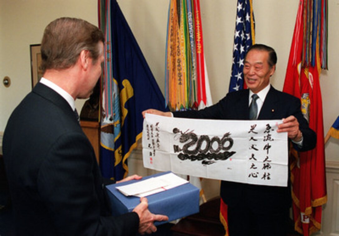 Director General of the Japan Defense Agency Tsutomu Kawara (right) presents Secretary of Defense William S. Cohen (left), a silk banner featuring a dragon curling its body to form the number ?." in the Pentagon on Jan. 5, 2000. Kawara was the first foreign guest of the new century to visit Cohen. 
