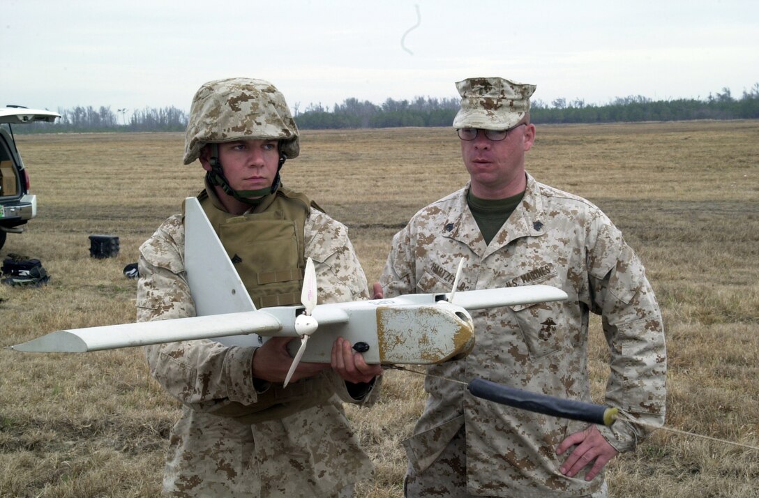 MARINE CORPS BASE CAMP LEJEUNE, N.C. - Corporal Ryan Vogt (left), a forward scout observer, Company B, 2d Light Armored Reconnaissance Battalion, holds the Dragon Eye unmanned aerial vehicle in preparation for launch during a course Jan. 12 at Tactical Landing Zone Falcon here. Vogt participated in the five-day Dragon Eye course with sole instructor Sgt. Michael Hartzfeld (right), Jan. 10 through 14, to learn how to properly operate the remote controlled piece of surveillance equipment. (Official Marine Corps photo by Lance Cpl. Matthew K. Hacker)