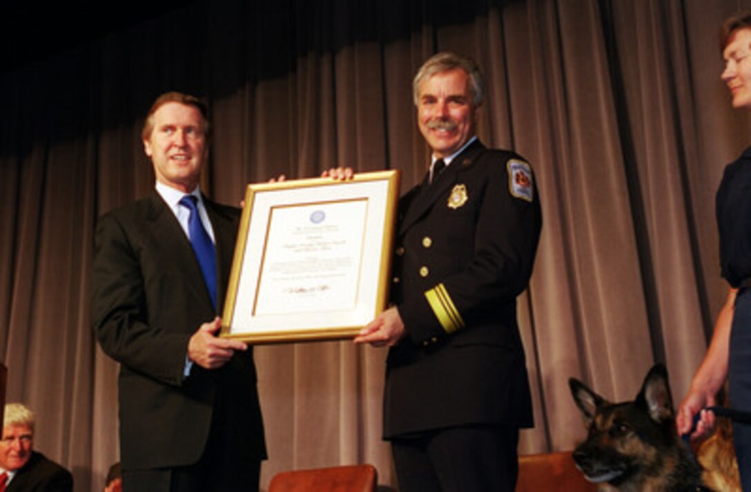 Secretary of Defense William S. Cohen (left) presents a Department of Defense citation to Assistant Chief Mark Wheatley of the Fairfax County Urban Search and Rescue Team at the Pentagon on June 27, 2000. The citation attests to the team's continuing tireless work and selfless dedication in providing humanitarian assistance to victims of disasters worldwide. Wheatley accepted the honor on behalf of the approximately 100 team members and three search dogs in the audience. 