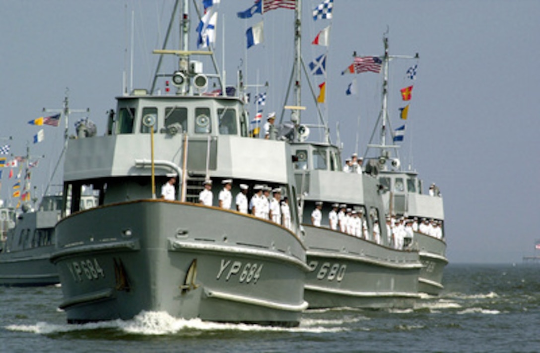 U.S. Naval Academy craft line up and the crews man the rail for a pass in review after returning to Annapolis, Md., on June 15, 2000, from a three week summer training cruise to New York, Newport, and Boston. Midshipmen as well as active duty officers and enlisted men take part in the annual training cruise. 