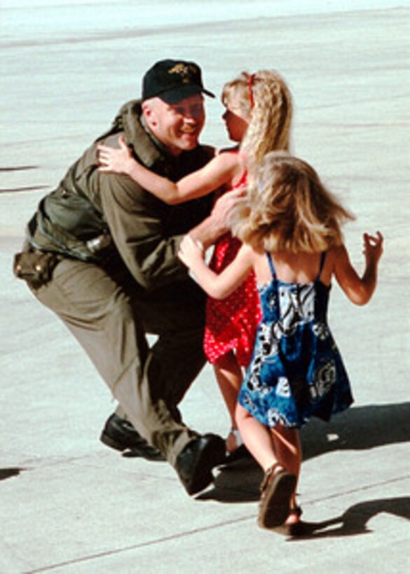 Petty Officer 1st Class Sam Wood rushes to embrace his daughters as he returns to Yigo, Guam, on June 29, 2000, from a five month deployment to the Persian Gulf aboard the combat stores ship USNS Niagara Falls. Wood, a Navy Aviation Electronics Technician, is assigned to Helicopter Combat Support Squadron 5. 