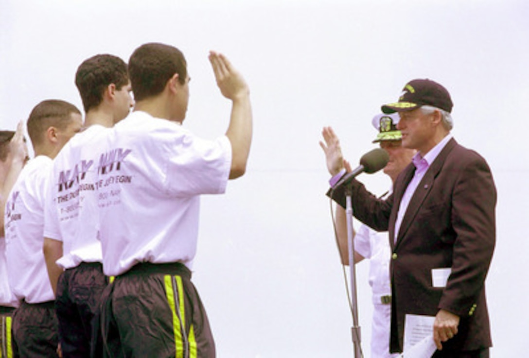 President Bill Clinton administers the oath of enlistment to new Navy recruits in a special ceremony on board the USS John F. Kennedy (CV 67) in New York harbor, on July 4, 2000. The president was on the aircraft carrier to receive honors from ships as they passed in review during the International Naval Review and Operation Sail 2000. 