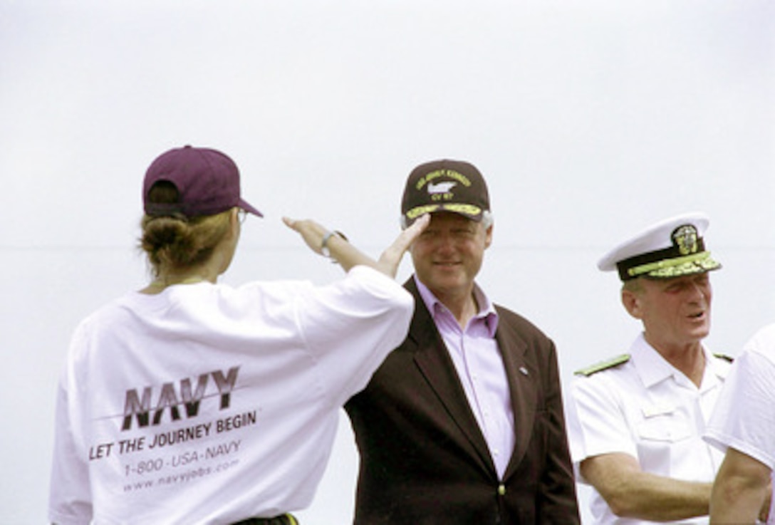 President Bill Clinton happily salutes a newly enlisted sailor following a special enlistment ceremony on board the USS John F. Kennedy (CV 67) in New York harbor, on July 4, 2000. Clinton administered the oath of enlistment to a group of Navy recruits on the carrier's flight deck. The president was on the aircraft carrier to receive honors from ships as they passed in review during the International Naval Review and Operation Sail 2000. 