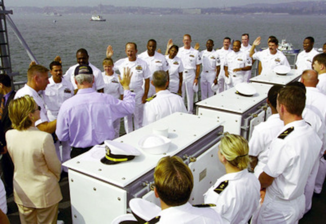 President Bill Clinton (in blue shirt) reads the oath of re-enlistment to a group of sailors aboard the USS Hue City (CG 66) on July 4, 2000, in New York Harbor. The president is aboard the Ticonderoga class cruiser to review naval units from around the world for the International Naval Review 2000. First Lady Hillary Rodham-Clinton, watches the ceremony on the president's left. 