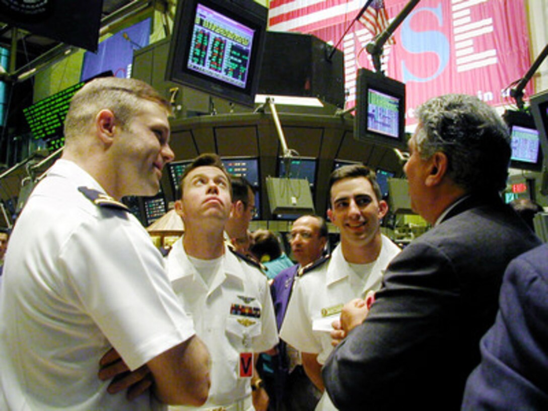 Bull Ensigns Pete Sommers, Eric Sadler, and Benjamin Andrew talk with a trader on the floor of the New York Stock Exchange as they participate in the International Naval Review's Bulls on Wall Street event in New York City on July 6, 2000. A bull ensign is traditionally the most senior ensign onboard a U.S. Navy ship and is tasked with teaching the newer ensigns the ways of life at sea. 