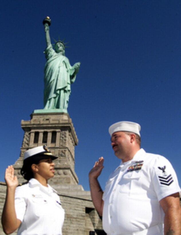 Everyone raises their right hand as Ensign Maria Navarro (left) administers the oath of re-enlistment to Petty Officer 1st Class John Carruthers at the base of the Statue of Liberty on Liberty Island, New York, on July 7, 2000. Navarro and Carruthers are two of over 25,000 international sailors and Marines from 20 countries in New York for International Naval Review 2000, a week-long event billed as a Celebration of Seapower for the Millennium. Navarro and Carruthers are stationed aboard the Ticonderoga Class Cruiser USS Hue City (CG 66). 