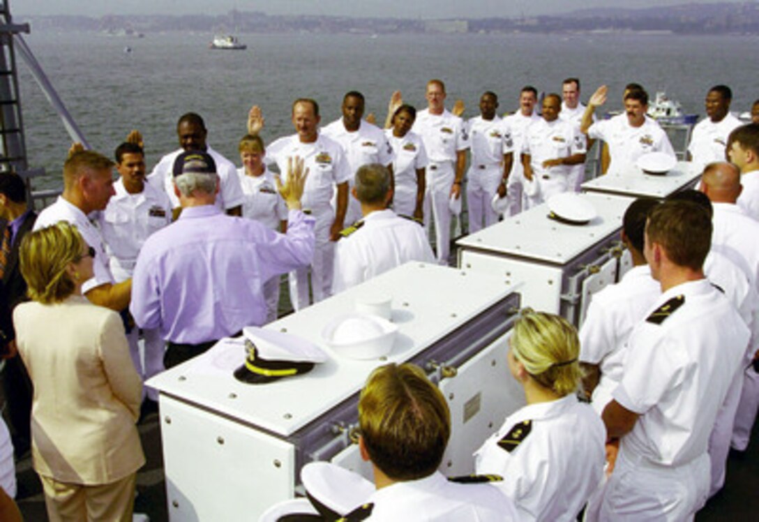 President Bill Clinton (in blue shirt) reads the oath of re-enlistment to a group of sailors aboard the USS Hue City (CG 66) on July 4, 2000, in New York Harbor. The president is aboard the Ticonderoga class cruiser to review naval units from around the world for the International Naval Review 2000. First Lady Hillary Rodham-Clinton, watches the ceremony on the president's left. 