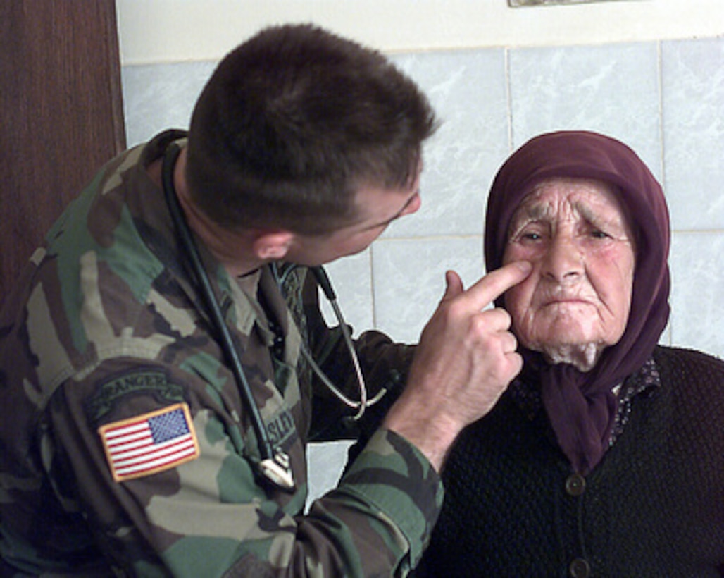1st Lt. John Slevin, a U.S. Army physician's assistant, checks the face of an elderly Serbian woman during a medical civil assistance program in the village of Silovo, Kosovo, on May 5, 2000. Slevin is attached to Headquarters and Headquarters Company, 1st Brigade, 63 Armor Battalion, of Veilseck, Germany, and is deployed to Kosovo, as part of KFOR. KFOR is the NATO-led, international military force in Kosovo on the peacekeeping mission known as Operation Joint Guardian. 