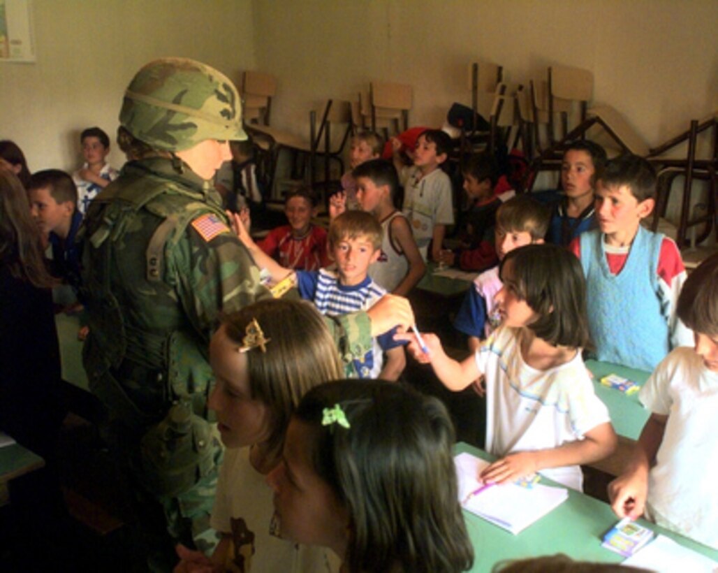 North Dakota Army National Guard Sgt. Tammy Nesheim hands out pens and pencils to students in a schoolhouse in Sodovina e Jerlive, a small Albanian village near Vitina, Kosovo, on May 19, 2000. Nesheim and her fellow soldiers from Headquarters Support Company, 142nd Engineer Battalion, North Dakota Army National Guard, are delivering boxes of clothing and school supplies donated to the kids in this small village by the soldiers' families and churches back home. Soldiers of the 142nd are deployed to Kosovo, as part of KFOR. KFOR is the NATO-led, international military force in Kosovo on the peacekeeping mission known as Operation Joint Guardian. 