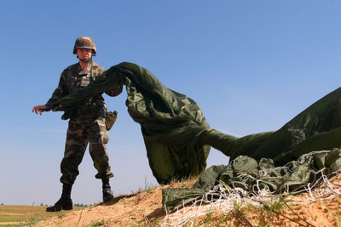 U.S. Army 1st Lt. Kenny Hamilton recovers his parachute after jumping from a C-130 Hercules onto the Sicily drop zone at Fort Bragg, N.C. on May 5, 2000, during Air Mobility Rodeo 2000. Rodeo 2000 is the U.S. Air Force Air Mobility Command's premier air mobility competition, involving more than 80 aircraft and 100 teams from 17 countries. The teams will compete in airdrops, aerial refueling, aircraft navigation, special tactics, short field landings, cargo loading, engine running on and off load, aeromedical evacuations and security forces operations. Hamilton is attached to the 1st Battalion, 321st Field Artillery Regiment, Fort Bragg, N.C. 