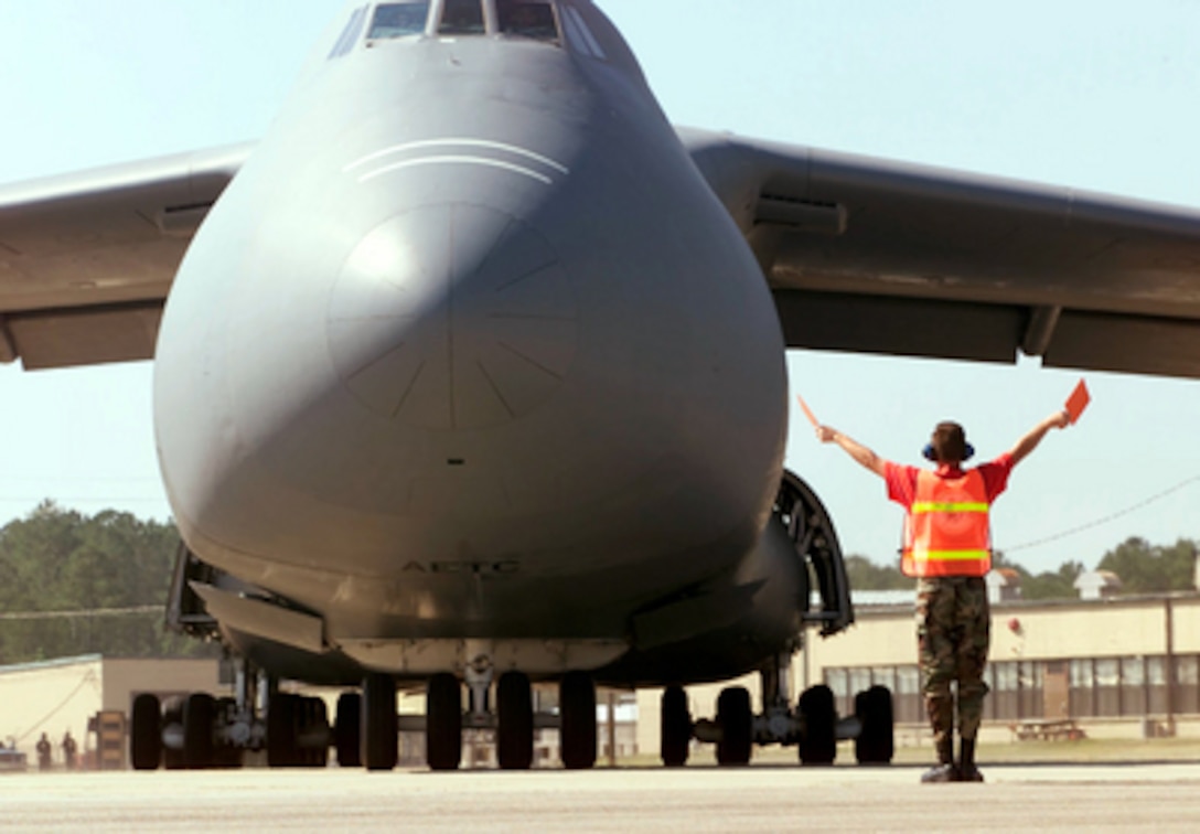 A U.S. Air Force C-5 Galaxy is directed to a parking spot on the ramp as it arrives at Pope Air Force Base, N.C., on May 6, 2000, for Air Mobility Rodeo 2000. Rodeo 2000 is the U.S. Air Force Air Mobility Command's premier air mobility competition, involving more than 80 aircraft and 100 teams from 17 countries. The teams will compete in airdrops, aerial refueling, aircraft navigation, special tactics, short field landings, cargo loading, engine running on and off load, aeromedical evacuations and security forces operations. The Galaxy is attached to the 436th Airlift Wing Reserve, Dover Air Force Base, Del. 