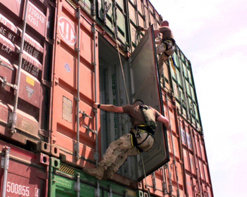 Boarding team members from the USS Lake Champlain (CG 57) rappel down cargo containers stacked on the deck of the merchant ship Puerto Cortes while it is stopped on a routine inspection in the Persian Gulf on May 15, 2000. The Lake Champlain is conducting Military Interdiction Operations in the Persian Gulf to locate merchant vessels suspected of violating United Nations embargoes. The Ticonderoga class cruiser is deployed to the Gulf from its home port of San Diego, Calif. 