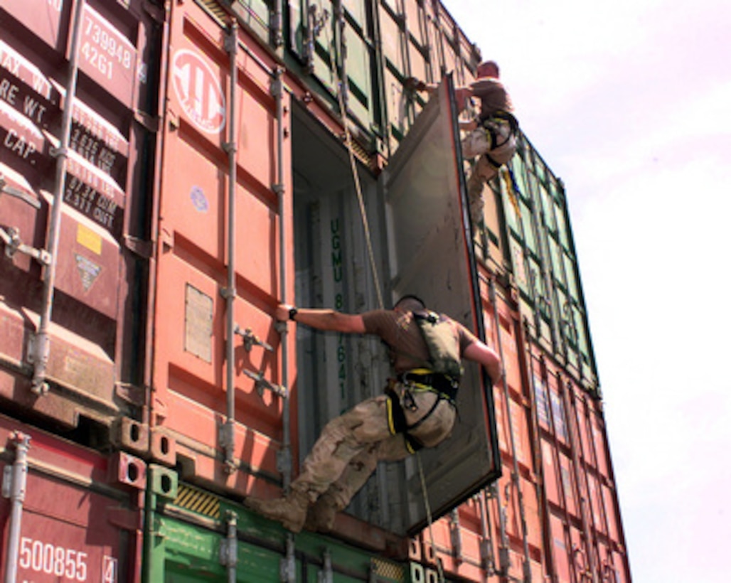 Boarding team members from the USS Lake Champlain (CG 57) rappel down cargo containers stacked on the deck of the merchant ship Puerto Cortes while it is stopped on a routine inspection in the Persian Gulf on May 15, 2000. The Lake Champlain is conducting Military Interdiction Operations in the Persian Gulf to locate merchant vessels suspected of violating United Nations embargoes. The Ticonderoga class cruiser is deployed to the Gulf from its home port of San Diego, Calif. 