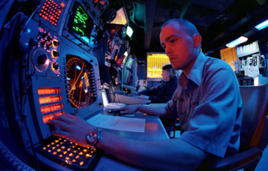 Petty Officer 3rd Class Michael Eubanks works in the blue light of the Electronic Warfare module as he stands the Advanced Combat Direction Systems watch aboard the aircraft carrier USS Kitty Hawk (CV 63) on June 3, 2000. Eubanks, from Dallas, Texas, is a Navy electronic warfare technician. The Kitty Hawk is home ported in Yokosuka, Japan. 