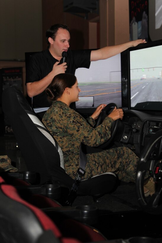 Christopher Rich, a public speaker with the Save a Life Tour, helps a Marine with a drunk driving simulator designed to let Marines experience what driving is like as a drunk driver during the Save a Life Tour rally Nov. 30, 2010, at Sunset Cinema.::r::::n::