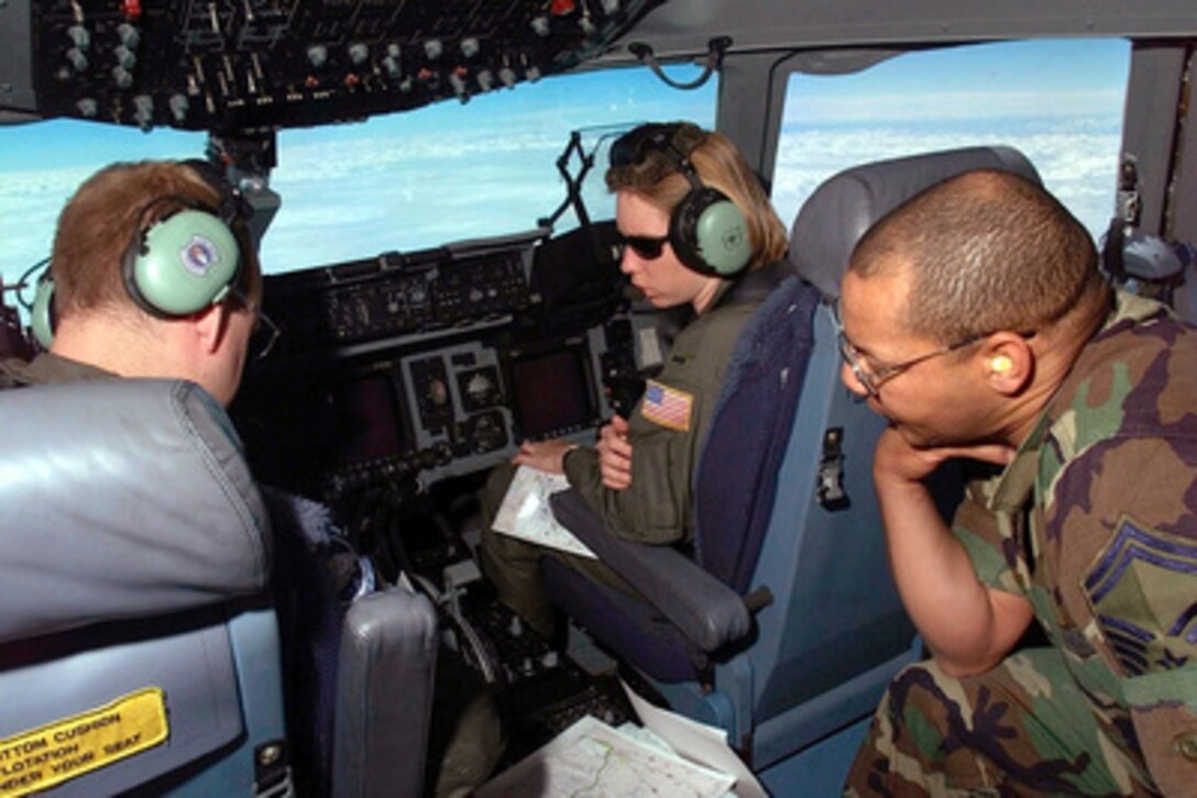 Senior Master Sgt. Libby Quinlan (right), Lts. Erin Markwith (center) and James Beyer (left) radio ahead for information on their destination of Hoedspruit Air Force Base, South Africa, on March 5, 2000. The crew of the U.S. Air Force C-17A Globemaster III is delivering personnel and cargo to Hoedspruit for Operation Atlas Response. Operation Atlas Response is the U.S. military's contribution to relief efforts following torrential rains and flooding in southern Mozambique and South Africa. The C-17A is the first of several flights that will bring helicopters and military personnel to assist with search and rescue and with the distribution of relief supplies. Quinlan is an air transportation manager assigned to the 721st Air Mobility Squadron, McGuire Air Force Base, N.J. Markwith and Beyer are pilots assigned to the 17th Airlift Squadron, Charleston Air Force Base, S.C. 