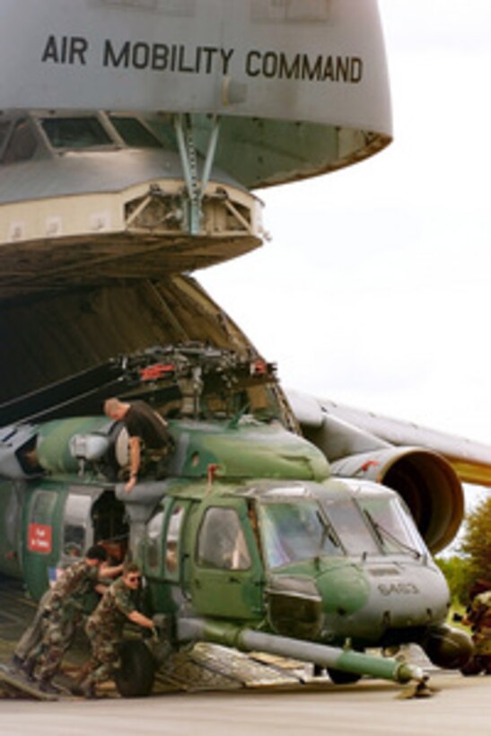 Members of the 41st Rescue Squadron from Moody Air Force Base, Ga., push a HH-60 Pave Hawk helicopter out of a U.S. Air Force C-5 Galaxy transport aircraft at Hoedspruit Air Force Base, South Africa, on March 7, 2000. The Galaxy is delivering cargo, personnel and two HH-60 Pave Hawk helicopters to Hoedspruit for Operation Atlas Response. Operation Atlas Response is the U.S. military's contribution to relief efforts following torrential rains and flooding in southern Mozambique and South Africa. The helicopters will aid in the distribution of relief supplies and rescue stranded flood victims. 