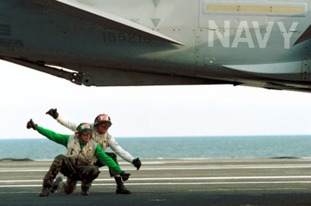 Two members of the Strike Fighter Squadron 83 flight deck crew give the thumbs up for the catapult launch of one of the squadron's F/A-18C Hornets from the deck of the USS George Washington (CVN 73) on March 1, 2000. The aircraft carrier is conducting carrier qualifications in the Atlantic Ocean. The Strike Fighter Squadron 83 Rampagers are deployed to the carrier from Naval Air Station Oceana, Va. 