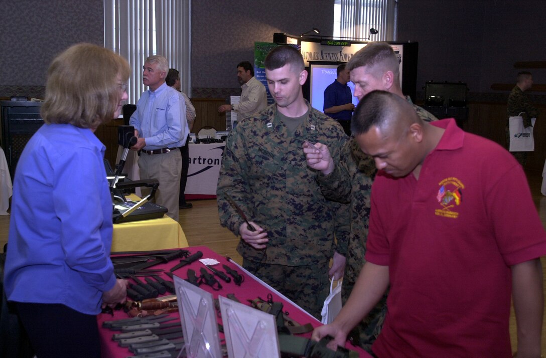 MARINE CORPS BASE CAMP LEJEUNE, N.C. - K. Sue Green, the quality control manager and contract administrator of Ontario Knife Company, stands behind her exhibit and talks to Marines about her company's products and how they will benefit them at the Annual Technology Exposition at Marston Pavilion March 16. The Armed Forces Communications and Electronics Association hosted the exposition and displayed over 30 manufacturing companies, each with their share of the latest state-of-the-art technology. (Official Marine Corps photo by Lance Cpl. Matthew K. Hacker)