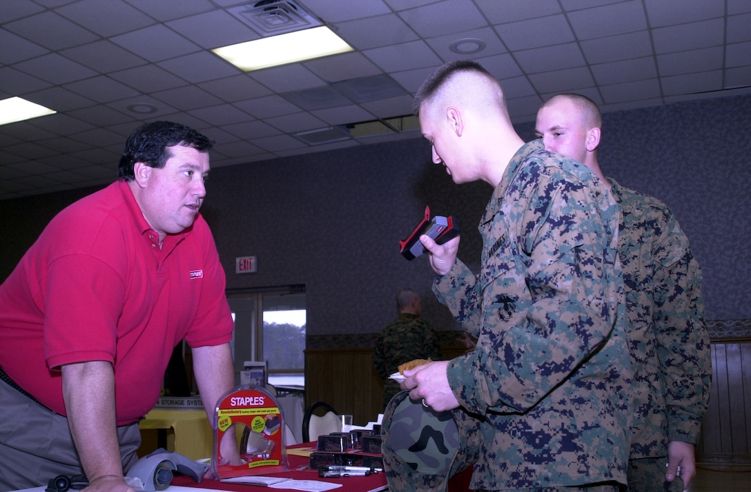 MARINE CORPS BASE CAMP LEJEUNE, N.C. - A Staples National Advantage representative (left), stands behind his exhibit and talks to Marines about their company's new stapler that staples through 25 pages with the touch of a finger at the Annual Technology Exposition at Marston Pavilion March 16. The Armed Forces Communications and Electronics Association hosted the exposition and displayed over 30 manufacturing companies, each with their share of the latest state-of-the-art technology. (Official Marine Corps photo by Lance Cpl. Matthew K. Hacker)