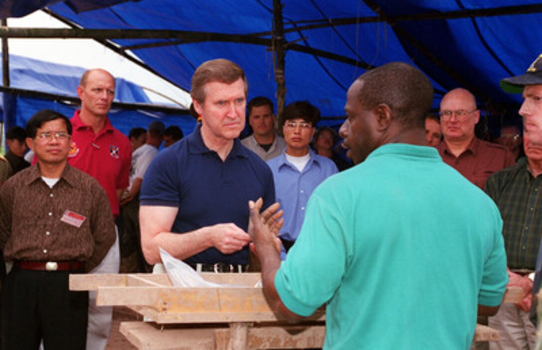 U.S. Air Force Master Sgt. Mark Mitchell (right), explains to Secretary of Defense William S. Cohen (center) what was found at a crash excavation site amid rice paddies outside Hanoi, Vietnam, on March 13, 2000. Cohen traveled to the site to see firsthand the efforts being made and the process involved in the search and recovery of the remains of U.S. servicemen unaccounted for during the Vietnam War. According to an eyewitness account, a Navy F-4B Phantom crashed at the site in May 1967. Mitchell is a life support specialist with Joint Task Force Full Accounting. 