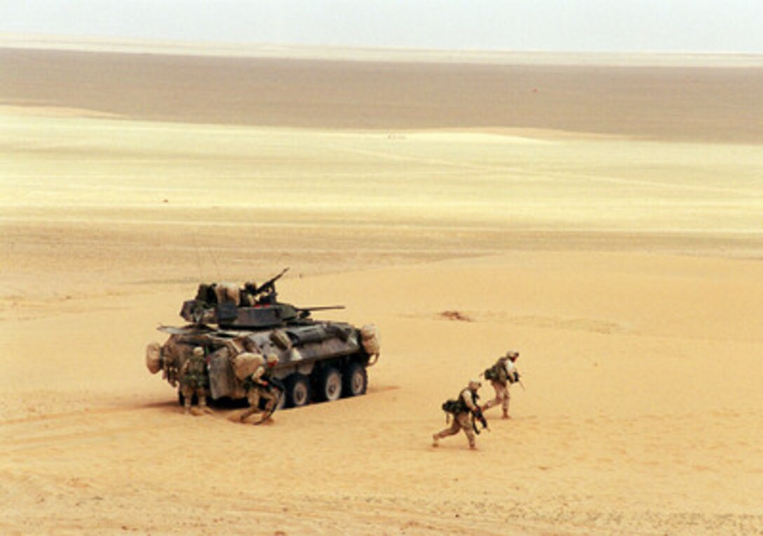 U.S. Marine Corps riflemen deploy from a Light Armored Vehicle (LAV-25) during a live-fire training exercise at the Udairi Training Range in northern Kuwait on April 8, 2000. After destroying the simulated enemy trucks with its turret-mounted 25 mm chain gun, the LAV deployed six Marine riflemen to deal with the remaining simulated enemy personnel. The LAV is attached to the 1st Light Armored Reconnaissance Battalion, 15th Marine Expeditionary Unit. 