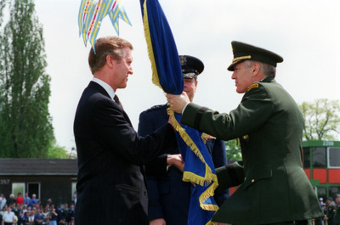 Outgoing Commander in Chief European Command Gen. Wesley Clark (right), U.S. Army, passes the European Command flag to Secretary of Defense William S. Cohen (left) who will pass it to Clark's successor Gen. Joseph W. Ralston (center), U.S. Air Force, during a change of command ceremony in Stuttgart, Germany, on May 2, 2000. Ralston is the former Vice Chairman of the Joint Chiefs of Staff. 