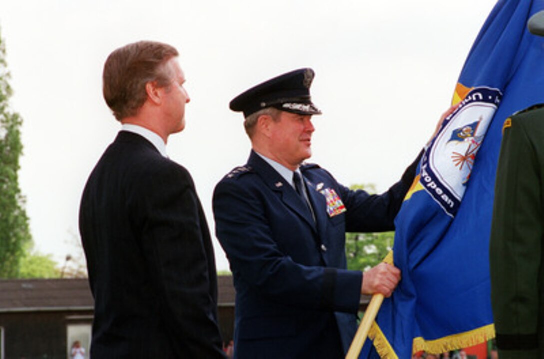 Gen. Joseph W. Ralston (right), U.S. Air Force, accepts the position of Commander in Chief European Command as he receives the European Command flag during a change of command ceremony in Stuttgart, Germany, on May 2, 2000. Secretary of Defense William S. Cohen (left) nominated Ralston for the job following his term as Vice Chairman of the Joint Chiefs of Staff. 